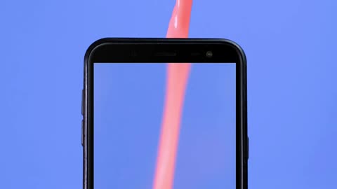 Cell phone filled with a pink liquid like a glass on a blue background