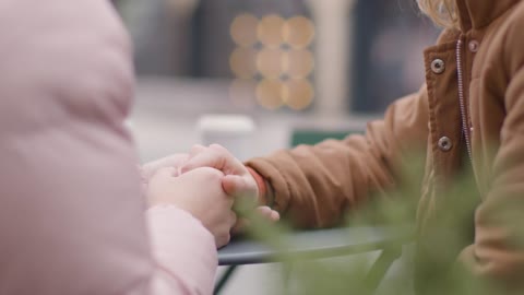 Close Up Shot of Two Young Women Holding Hands at Outdoor Table