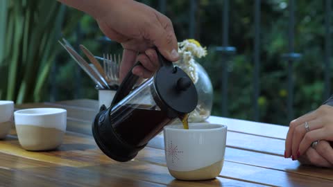 A waiter serves coffee to a customer