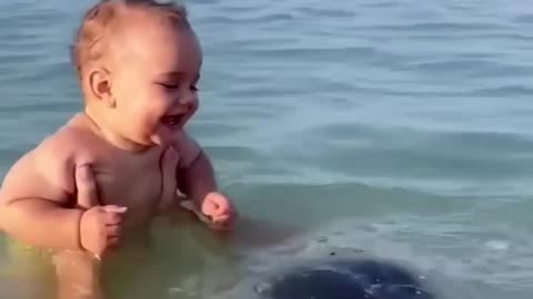 Cute baby laughing at the beach with dad