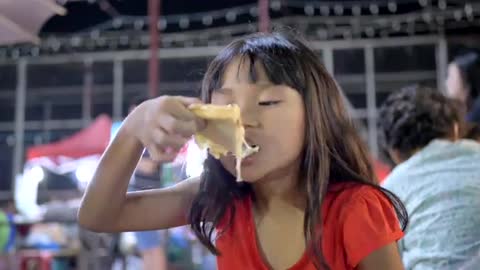 kids .. Little Girl Enjoys Eating At Street Food.