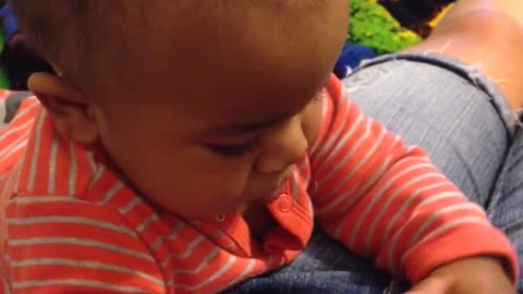Baby attempts to figure out button on pants