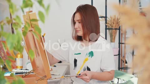 A Red Haired Young Woman Artist Painting A Frame