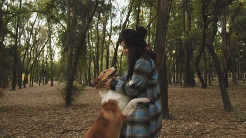 A woman caresses her dog in the park