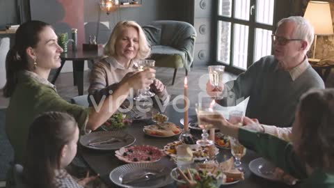 Happy Family Toasting Each Other While Having Dinner Together At Home