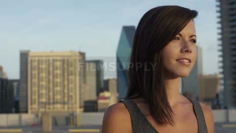 A brunette woman brushing her hair out of her face