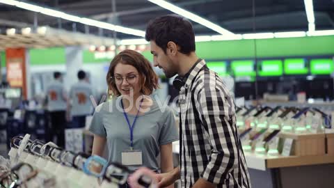 In The Electronics Store Female Consultant Gives Professional Advice To A Young Man 2