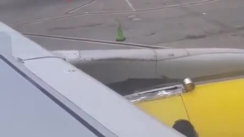 A passenger films an employee taping the wing of a plane before takeoff