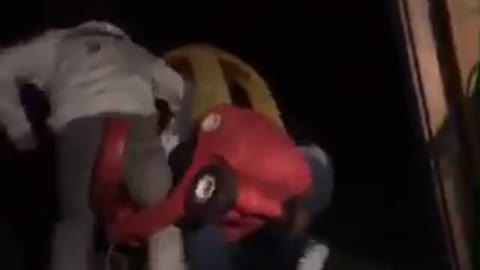 Two guys stuck inside of red and yellow toy car