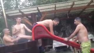 Music shirtless guy sliding down wet slide