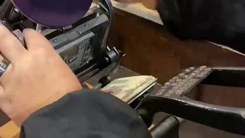 Using a tabletop printing press to print a blue picture of a printing press