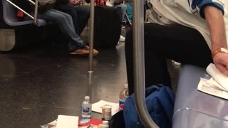 A man on a subway surrounded by his things on subway