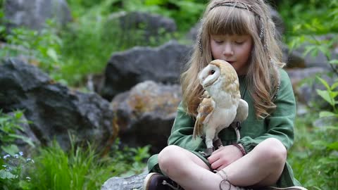 Little girl with an owl in a fairy forest. Friends