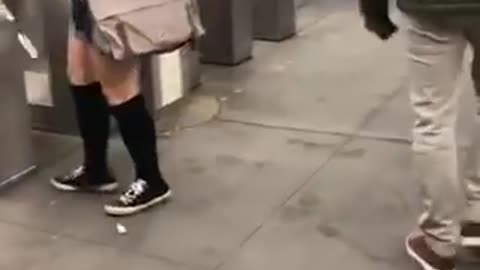Woman goes through subway turnstiles with a cardboard box on her head