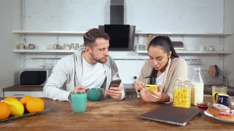 Couple having breakfast cereal and see their cell phones