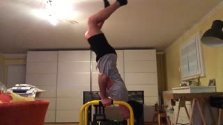 Guy tries to do handstand on yellow bars fails and hits leg on small green table
