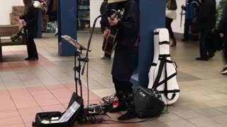 Man with basket on head plays guitar and sings on subway