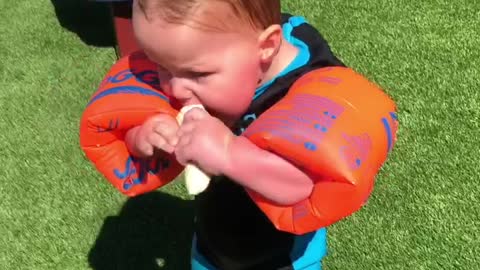 Baby Makes Hilarious Attempts To Eat A Banana While Wearing Floaties
