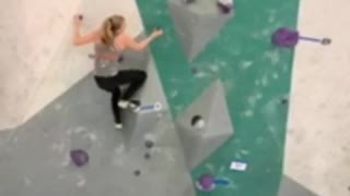 Woman in grey rock climbing indoors falls off