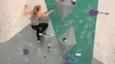 Woman in grey rock climbing indoors falls off