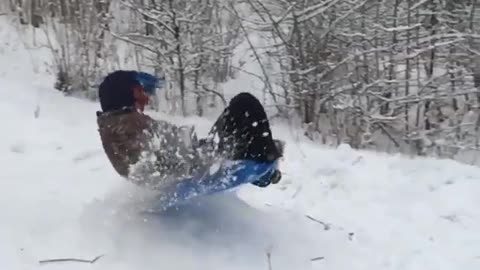 Kid in blue sled jumps ramp in slow mo and falls on face