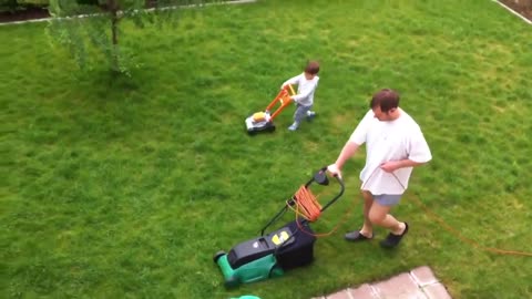 Father and son adorably mow the lawn together