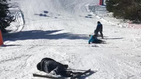 Skier in black and other in blue fall down slope