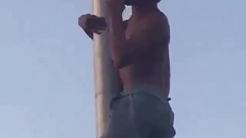 Shirtless jean shorts guy on flag pole drinking beer