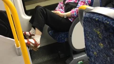 Old woman rubs belly on bus at night