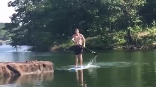 Guy on paddleboard gets tackled by friend