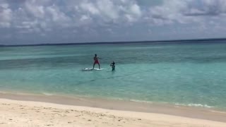 Guy red shorts surfboard friend in water taking picture