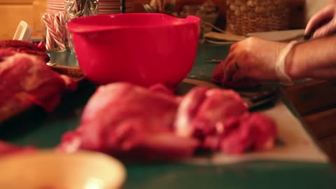 hunter cuts up slabs of elk meat on a kitchen counter