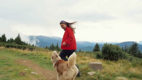 Young female playing and wrunning with siberian husky dog in mountains on path