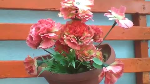 Beautiful red plastic flowers in the vase near of the wall [Nature & Animals]