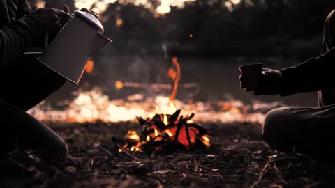 || People pouring a warm drink around a campfire ||