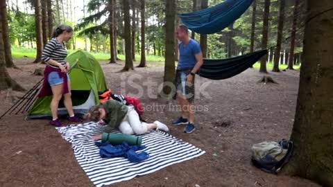 Careless man falling out of the hammock while camping with friends