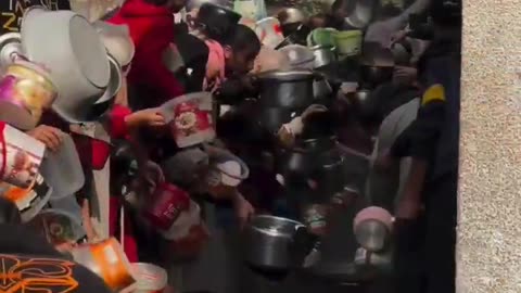 Displaced Palestinians line up to get food from a charitable hospice in Gaza