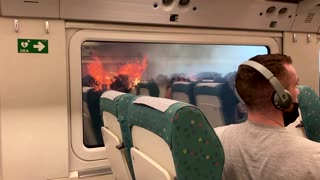 Passengers look on as wildfire rages near stuck train