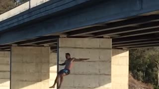 Shirtless man backflips off bridge and back flops in river