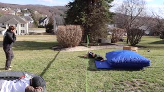 Guy jumps on slackline, trips and falls onto safety pad