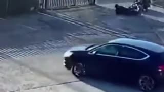 Security camera, guys turns out of a gate on motorcycle and falls over