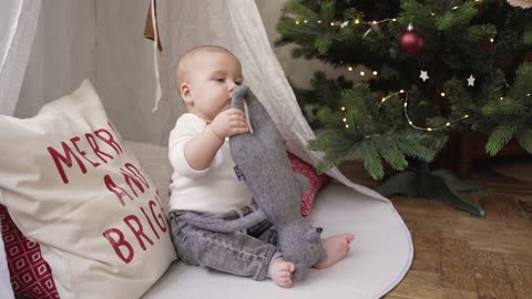 Cute Baby Playing on the Floor Beside Christmas Tree