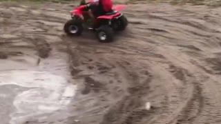 Red fourwheeler guy doing donuts in mud falls over