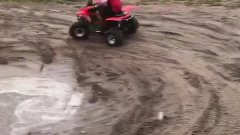 Red fourwheeler guy doing donuts in mud falls over