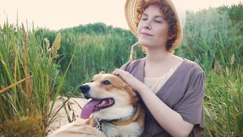 Happy corgi dog with the owner girl in the park near the reed