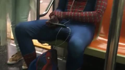 Man in spiderman suit and back pack blue hate subway