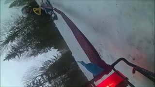 Snow mobile pulling sled falls over