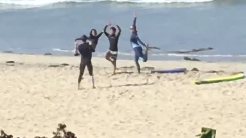 Girl sees three surfers on the beach posing for a picture
