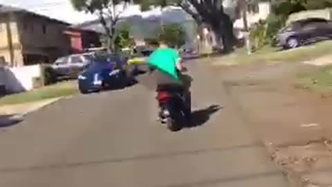 Man in green carrying surf board on moped