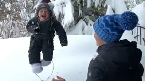 a baby is thrown into a snowdrift, which causes laughter